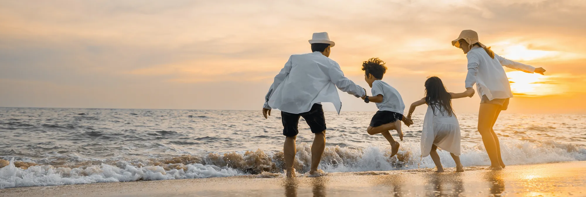 Family on beach having fun in the surf at sunset